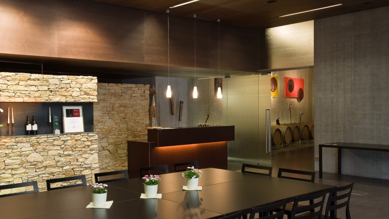 Moderner Verkostungsraum mit Holztisch, St&uuml;hlen und Steinwand.