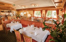 Elegantes Restaurant mit gedeckten Tischen und roten Polstermöbeln.