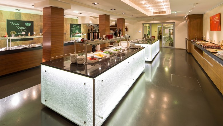 Modernes Buffet in einem Hotelrestaurant mit beleuchteten Theken und verschiedenen Speisen.