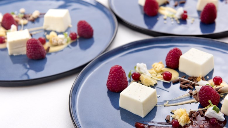 Elegante Dessertpr&auml;sentation auf blauen Tellern mit Himbeeren, Creme und Schokoladensplittern.