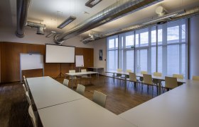 Seminarraum mit Tischen, St&uuml;hlen und Projektionsleinwand.