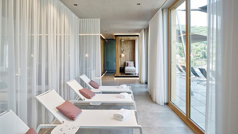 Moderner Spa-Bereich mit Liegest&uuml;hlen und gro&szlig;en Fenstern.