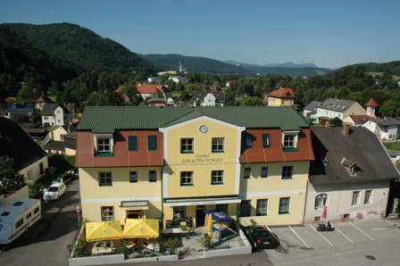 Außenansicht eines gelben Hotels mit grünem Dach in einer ländlichen Umgebung.
