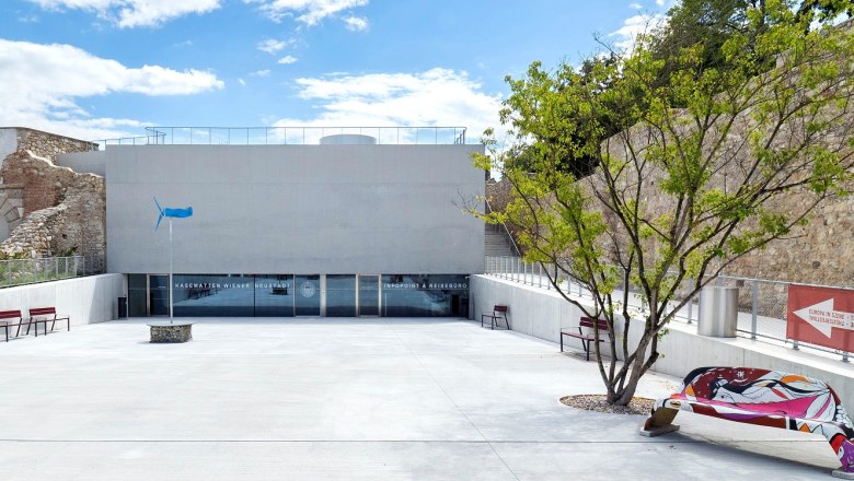 Eingang zu den Kasematten in Wiener Neustadt mit moderner Architektur und Kunstbank.