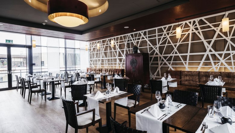 Elegantes Restaurant mit modernen asiatischen Designelementen, gedeckten Tischen und gro&szlig;en Fenstern.