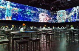 Ein moderner Showroom mit digitalen Projektionen und Tischen mit Blumen.