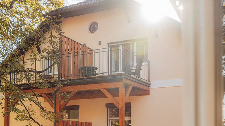 Haus mit Balkon und Sonnenschein durch B&auml;ume.