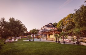 Großes Haus mit Garten und Pool bei Sonnenuntergang.