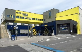Außenansicht des Multiversum Schwechat, einem modernen Gebäude mit gelben und blauen Fassaden.
