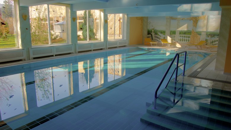 Innenpool im Hotel Marienhof mit großen Fenstern und Liegestühlen.