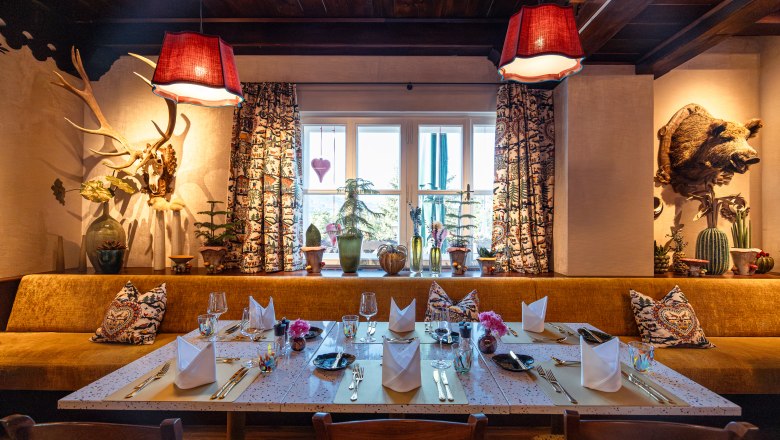 Gem&uuml;tlich dekoriertes Restaurant mit gedecktem Tisch, rustikalen Elementen und Pflanzen am Fenster.