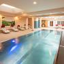 Ein moderner Indoorpool im Hotel-Spa mit Liegest&uuml;hlen und Wandmalereien