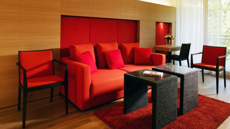 Moderne Suite mit roten M&ouml;beln und Holzw&auml;nden.