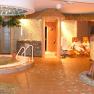 Ein Wellnessbereich mit Whirlpool, Liegestühlen und Personen in Bademänteln.