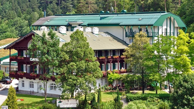 Ein großes Hotelgebäude mit grünen Dächern und Balkonen, umgeben von Bäumen und Natur.