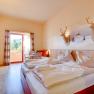 Hotelzimmer mit Doppelbett, Holzm&ouml;beln und Balkon mit Bergblick.