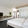 Modernes Hotelzimmer mit Doppelbett, Fernseher und Pflanzen.