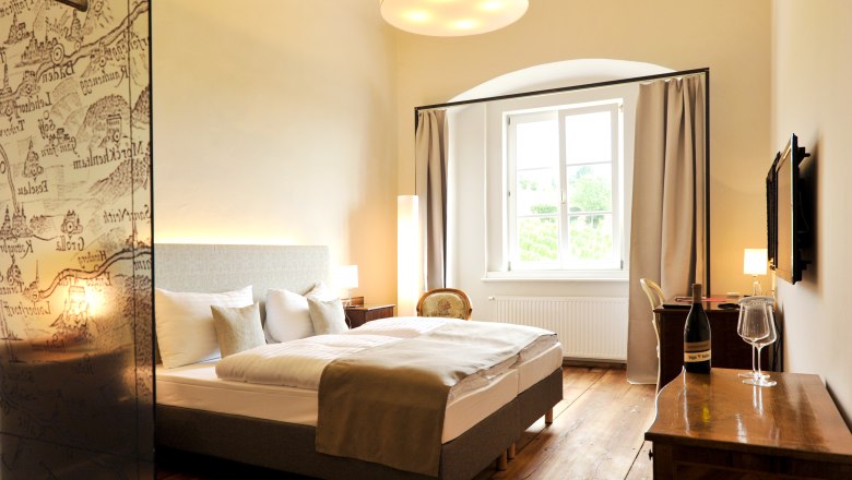 Elegantes Hotelzimmer mit Doppelbett, Holzboden und großem Fenster.
