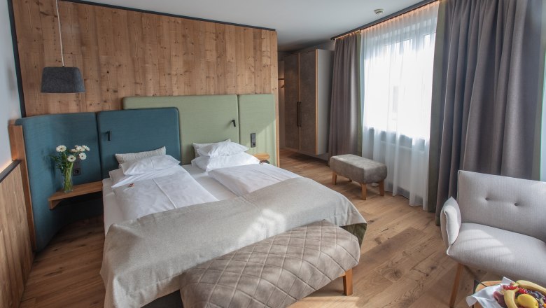 Modernes Hotelzimmer mit Doppelbett, Holzwänden und großen Fenstern.
