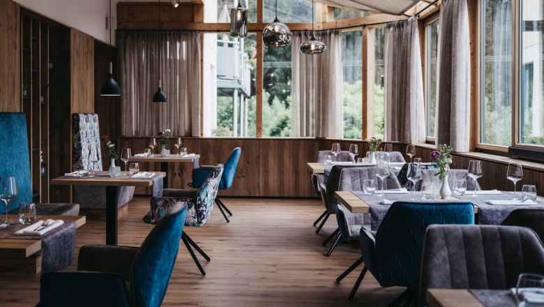 Elegantes Restaurant mit Holzboden, großen Fenstern und stilvoll gedeckten Tischen.