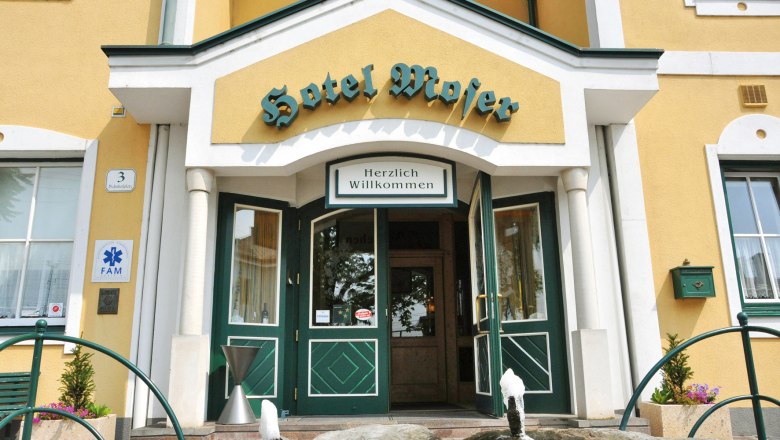 Eingang des Hotel Moser mit gelber Fassade und gr&uuml;nen T&uuml;ren.