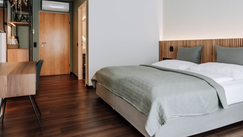 Modernes Hotelzimmer mit Doppelbett, Holzboden und Schreibtisch.