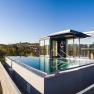 Dachpool mit Glasw&auml;nden auf einem modernen Geb&auml;ude, umgeben von Landschaft.