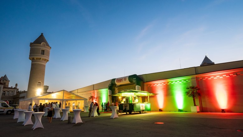 Abendveranstaltung im Freien mit beleuchtetem Gebäude und Zelten.