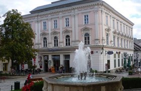 Historisches Gebäude mit Brunnen im Vordergrund.
