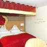 Gem&uuml;tliches Hotelzimmer mit rotem Baldachin und Rosenmotiv an der Wand.
