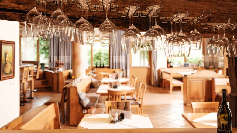 Innenansicht eines Restaurants mit h&auml;ngenden Weingl&auml;sern und Holzm&ouml;beln.