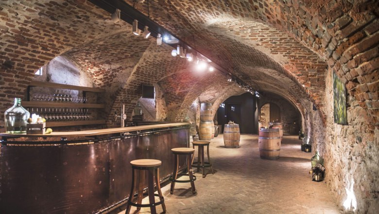 Historischer Schlosskeller mit Backsteinw&auml;nden, Bar und Holzf&auml;ssern.