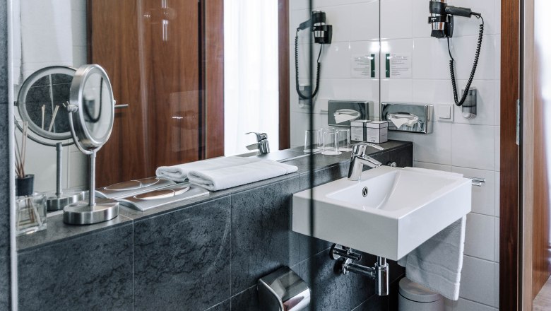 Modernes Hotelbadezimmer mit Waschbecken, Spiegel und Handtüchern.