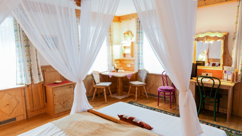 Gemütliches Doppelzimmer mit Himmelbett, Holzmöbeln und Schreibtisch.