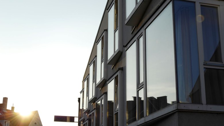 Moderne Geb&auml;udefassade mit gro&szlig;en Fenstern im Sonnenuntergang.