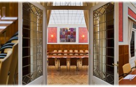 Konferenzraum im Hotel Herzoghof mit langen Tischen, St&uuml;hlen und Pr&auml;sentationsausstattung.