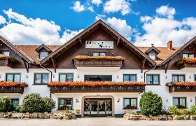 Ein traditionelles Hotel mit Holzbalkonen und Blumenkästen vor einem blauen Himmel.