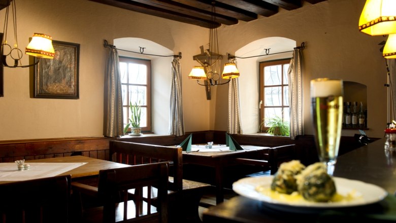 Gem&uuml;tliches Restaurant mit Holzm&ouml;beln, Bier und Kn&ouml;deln auf einem Tisch.