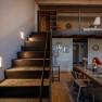 Innenansicht eines modernen Hotelzimmers mit Treppe, Tisch und Stühlen.