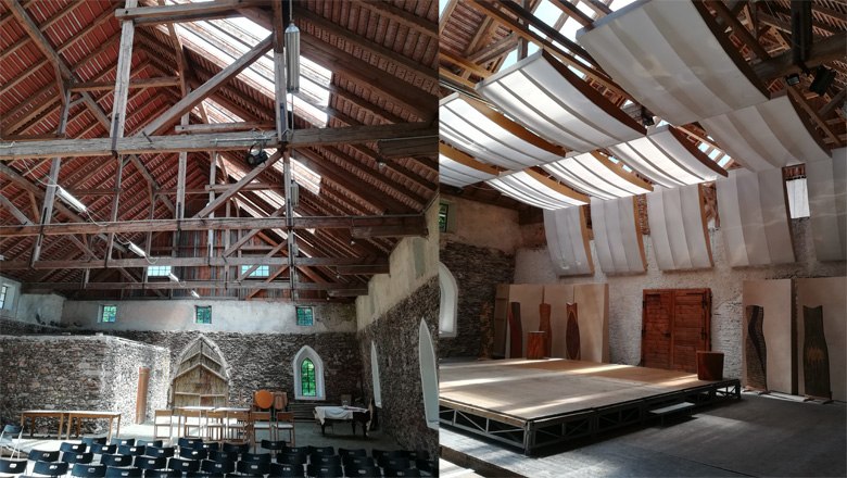 Innenansicht eines historischen Geb&auml;udes mit Holzdach und B&uuml;hne.