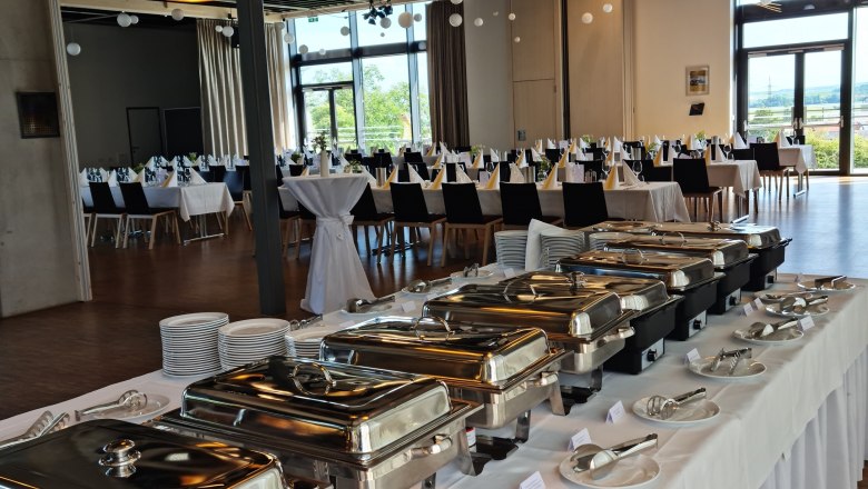 Ein festlich gedeckter Raum mit Buffet und gedeckten Tischen.