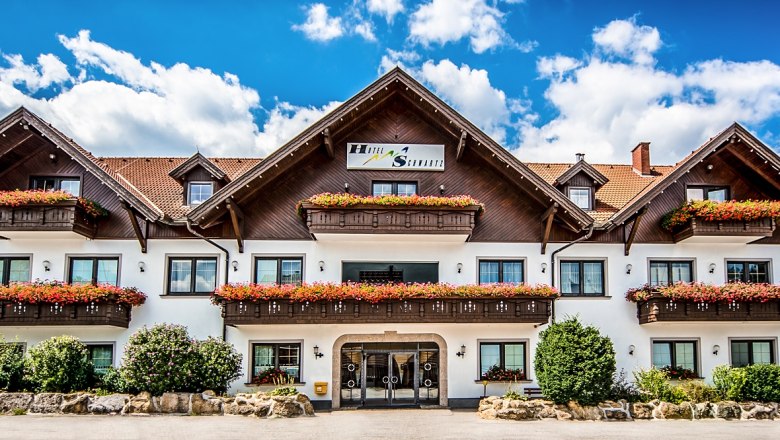 Ein traditionelles Hotel mit Holzbalkonen und Blumenk&auml;sten vor einem blauen Himmel.