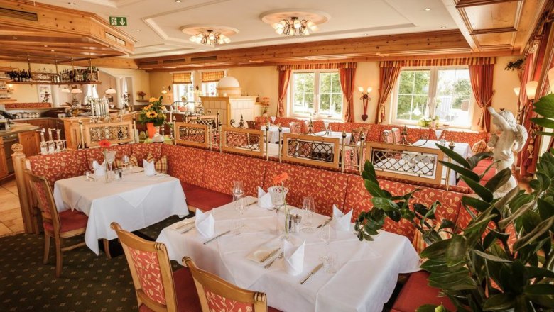 Elegantes Restaurant mit gedeckten Tischen und roten Polstermöbeln.