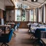 Elegantes Restaurant mit Holzboden, gro&szlig;en Fenstern und stilvoll gedeckten Tischen.
