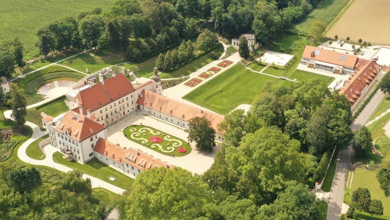 Luftaufnahme von Schloss Thalheim mit umliegenden Gärten und Gebäuden.