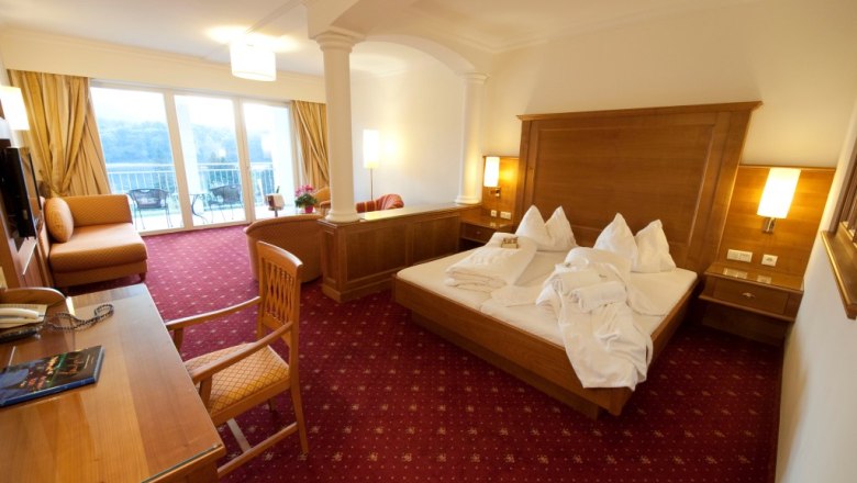 Hotelzimmer mit Doppelbett, Schreibtisch und Balkon mit Ausblick.