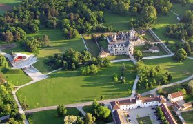 Luftaufnahme von Schloss Grafenegg mit umliegendem Park und moderner Bühne.