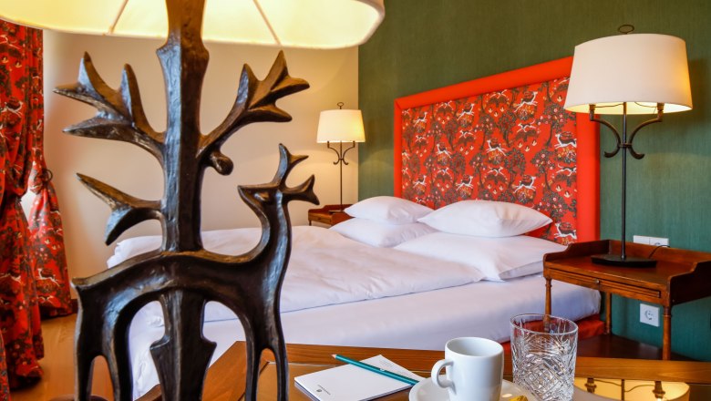 Ein stilvoll eingerichtetes Hotelzimmer mit einem Bett, dekorativen Lampen und einem Tisch mit Tasse und Glas.