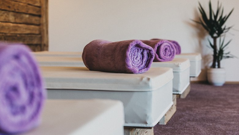 Wellnessbereich mit lila Handtüchern auf Liegen.