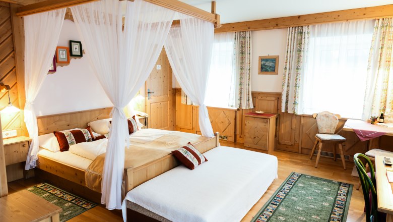 Gem&uuml;tliches Hotelzimmer mit Himmelbett, Holzm&ouml;beln und Teppichen.